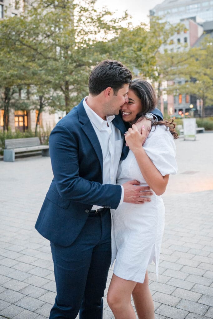 A couple laughs while embracing on the Rose Kennedy Greenway after engagement.