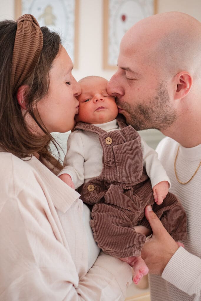 Wakefield photographer captures a couple kissing the cheeks of their newborn in this North Shore newborn session.