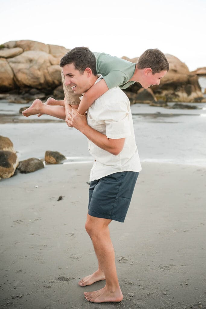 A north shore photographer captures a dad playing at the beach with his son as he throws his son over his shoulder.
